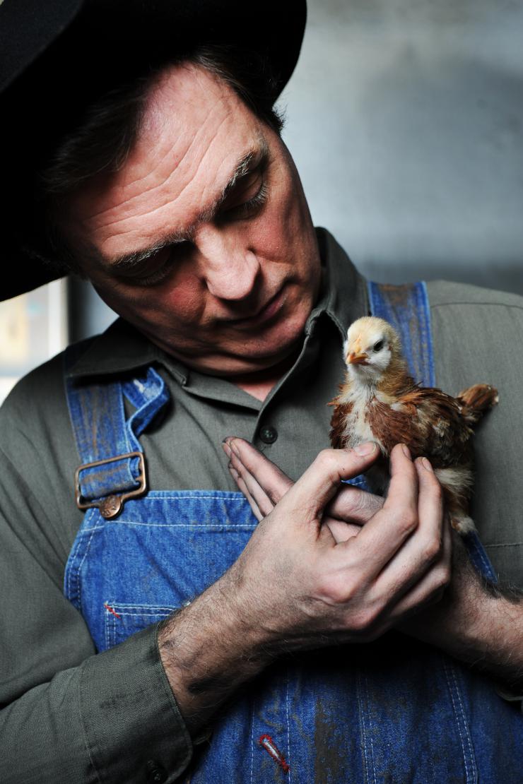A man holding a baby chick. 