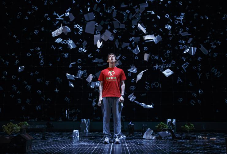 actor on stage surrounded by paper
