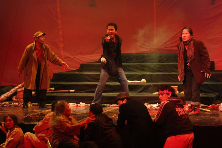 actors standing and crouching on a red stage, performing concern