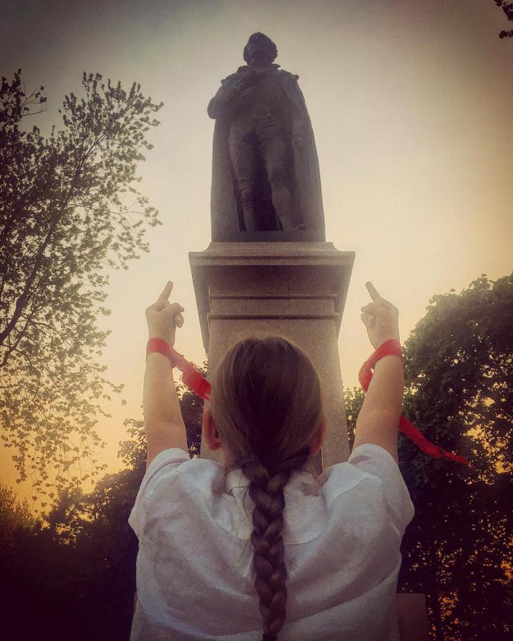 Woman with red wristbands flipping off a statue
