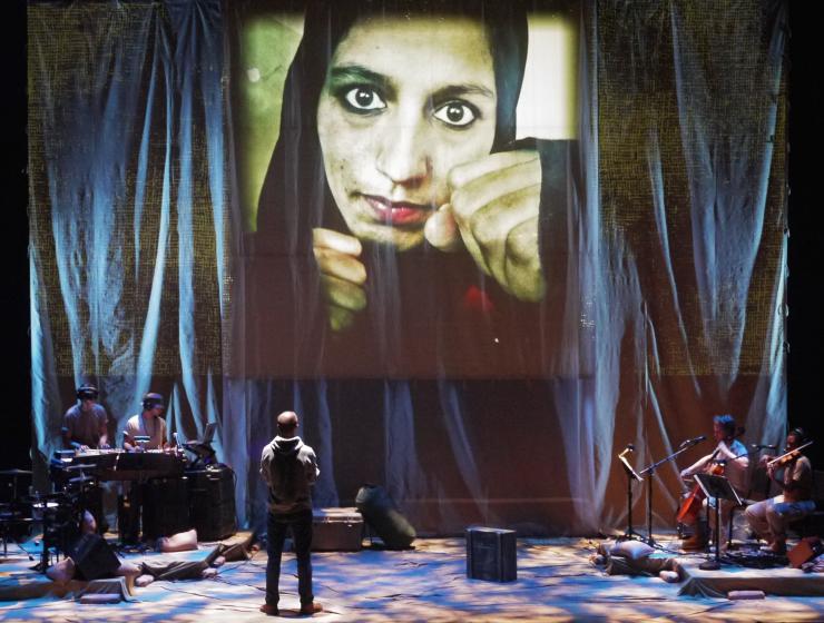 An actor with projections and a band on stage 