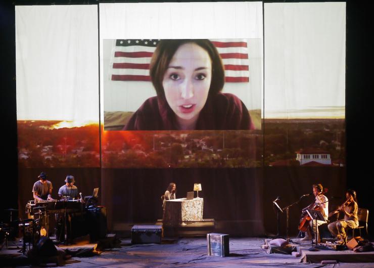 an actor with projections and band on stage 