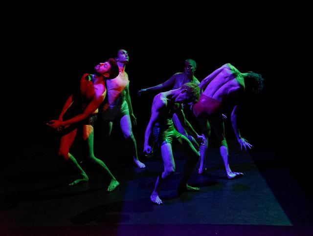 five performers dance in colored light