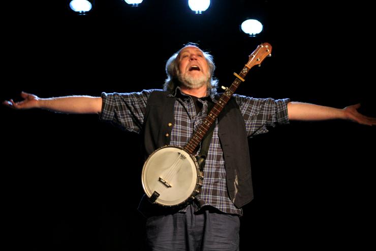 Actor holding out arms, wearing a banjo