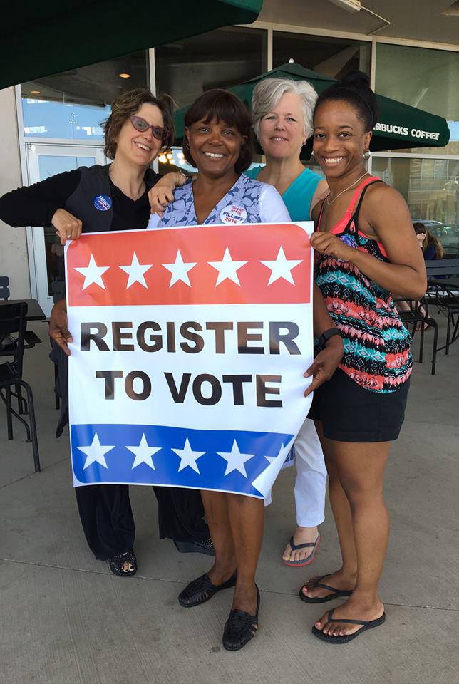 women holding a "register to vote" sign