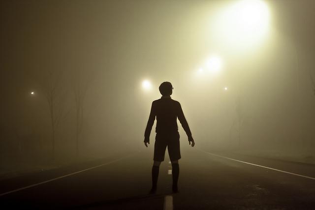 a person looking down a road into fog