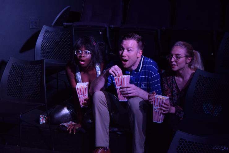 three performers onstage eating popcorn