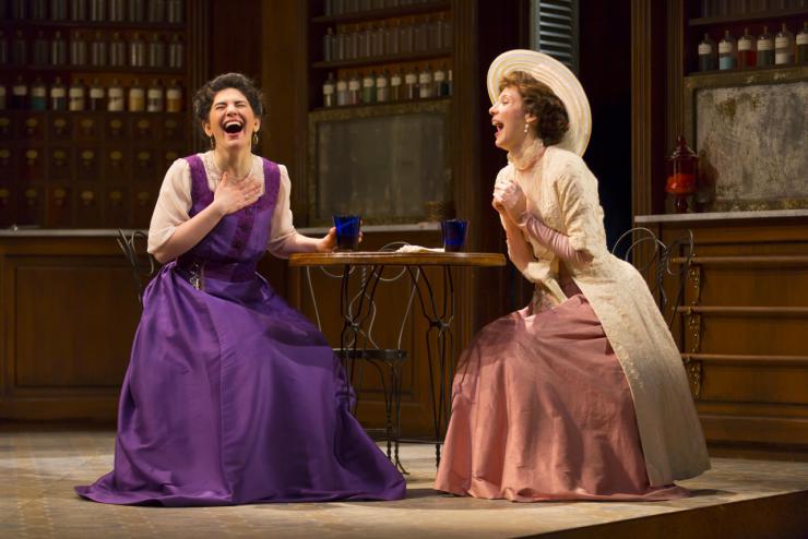 two women in period costumes laughing on stage