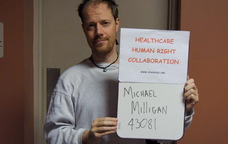 Michael Milligan holding a sign saying: Health Care Human Right Collaboration