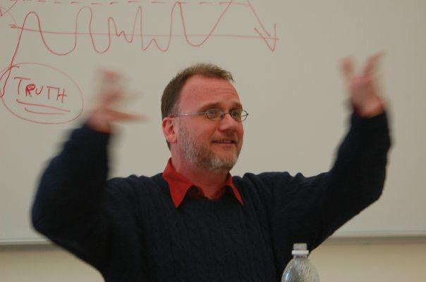 a professor waving his arms and speaking