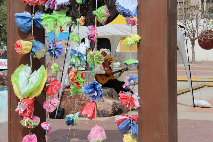 man playing the guitar behind a set of paper flowers