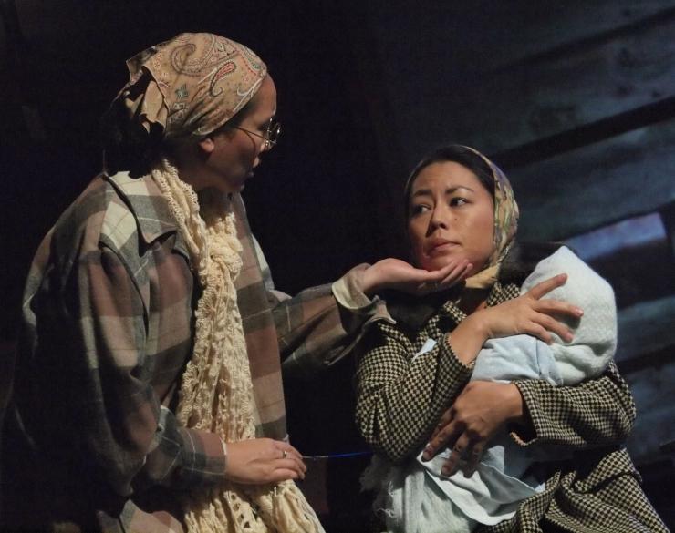 two women holding a child on stage