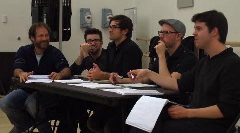 People seated at a table in a rehearsal room.