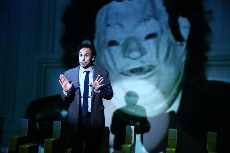 An actor in front of a projection of a masked figure