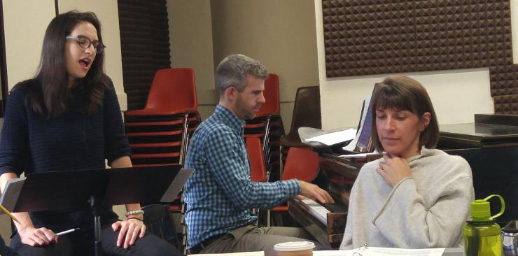 a director listens to an actor singing in rehearsal, while a pianist accompanies them