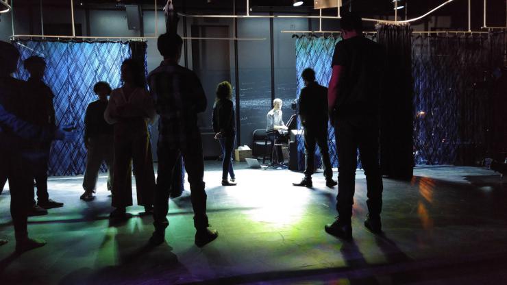 the silhouettes of performers moving in a dimly lit room