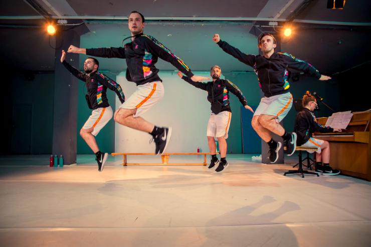 four actors in matching outfits jumping