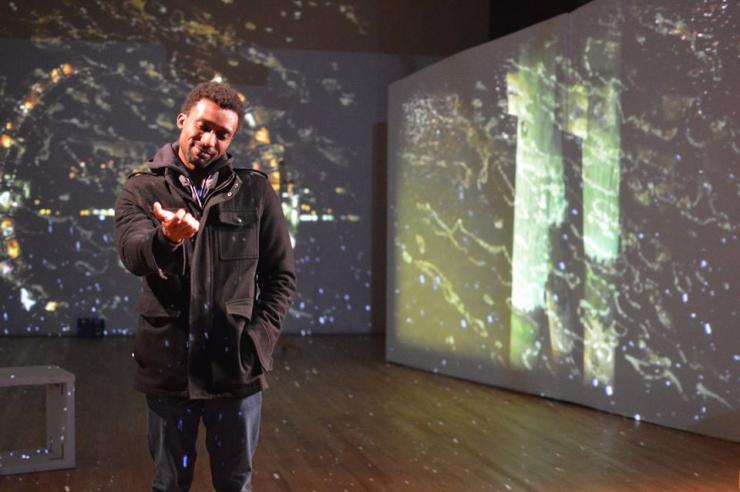 Man looking at his hand in front of projections of stars