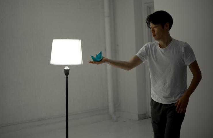 A man holds a blue boat toward a lamp