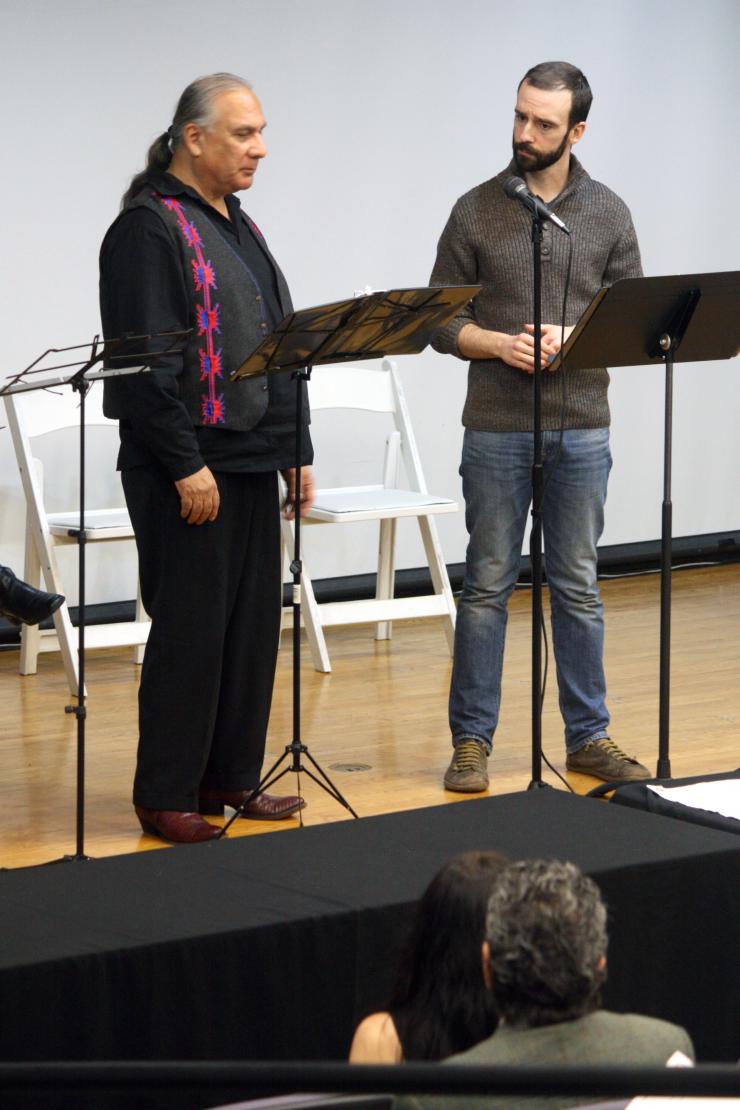 Two performers reading on stage 