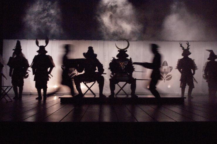 several silhouettes of actors in costume on stage