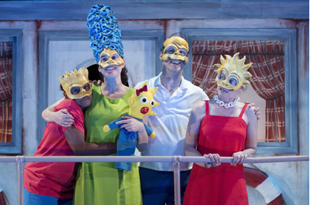 The cast on stage, in masks 