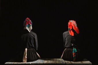 Two actors in traditional Roma women clothing with their backs to us.