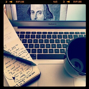 photo of laptop with notebook, mug, and an image of Shakespeare