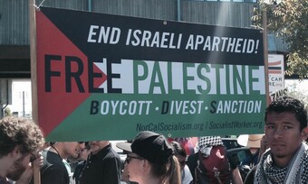 A Palestinian flag that says, "End Israeli Apartheid! Free Palestine. Boycott-Divest-Sanction. NorCalSocialism.org/SocialistWorker.org."