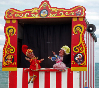 A puppet booth with two puppets in the window.