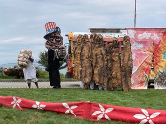 Several performers with large puppets standing in a field.