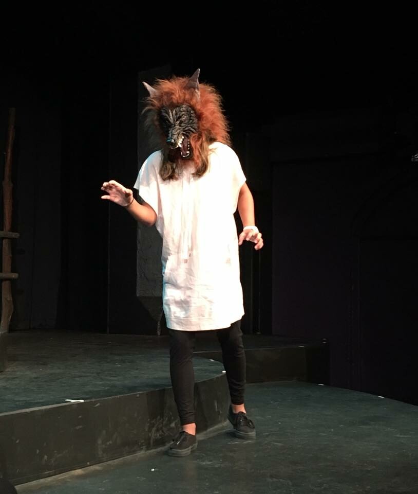 Actor on stage wearing a wolf mask