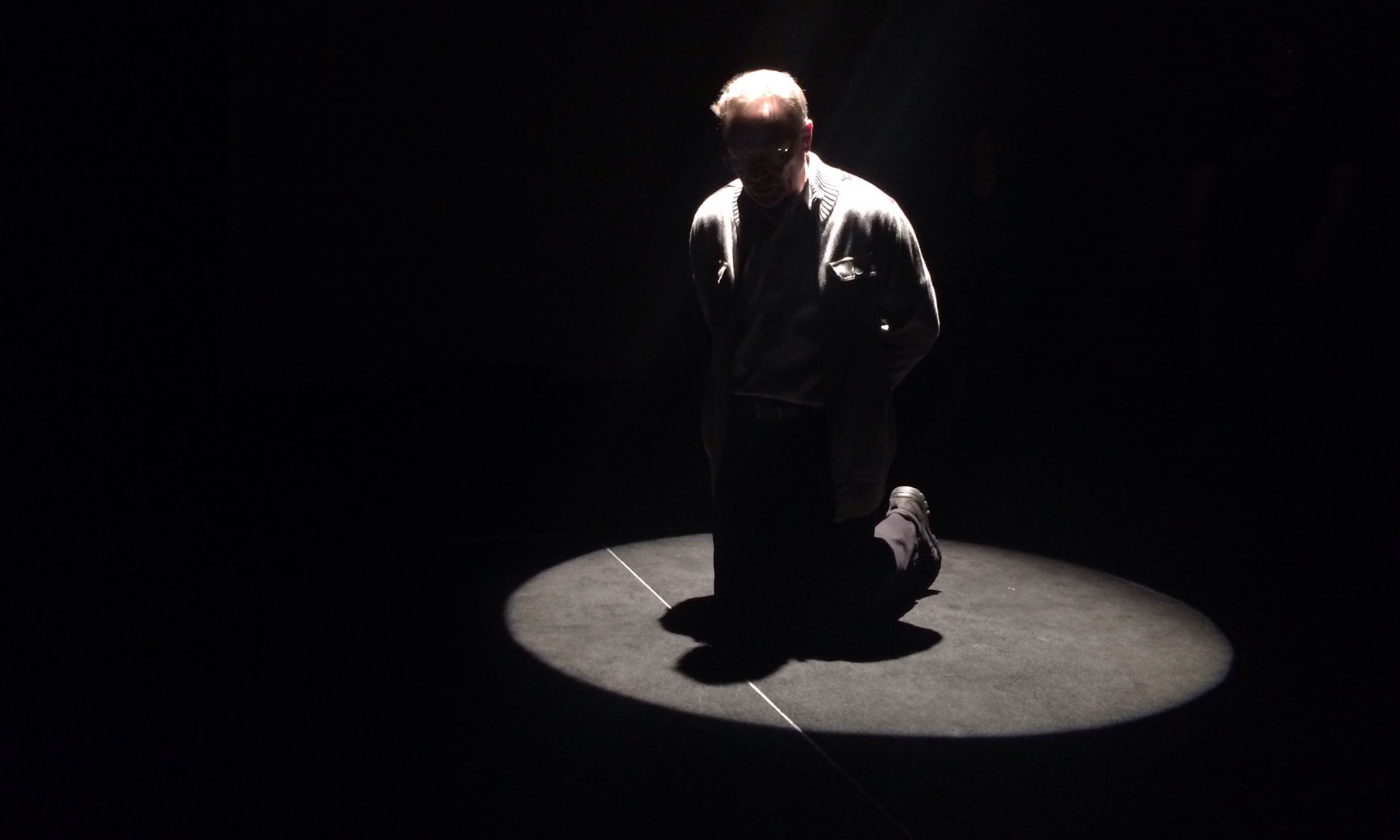 an actor kneeling in a spotlight