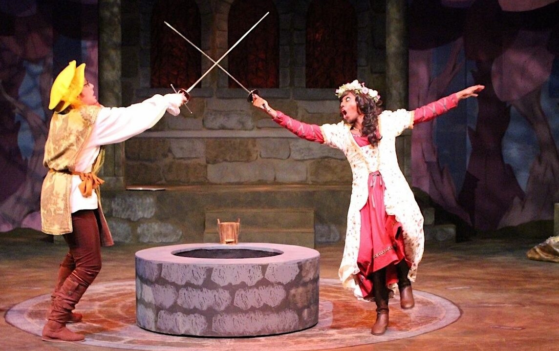 An image of two actors dressed in medieval period clothing having a sword fight. 