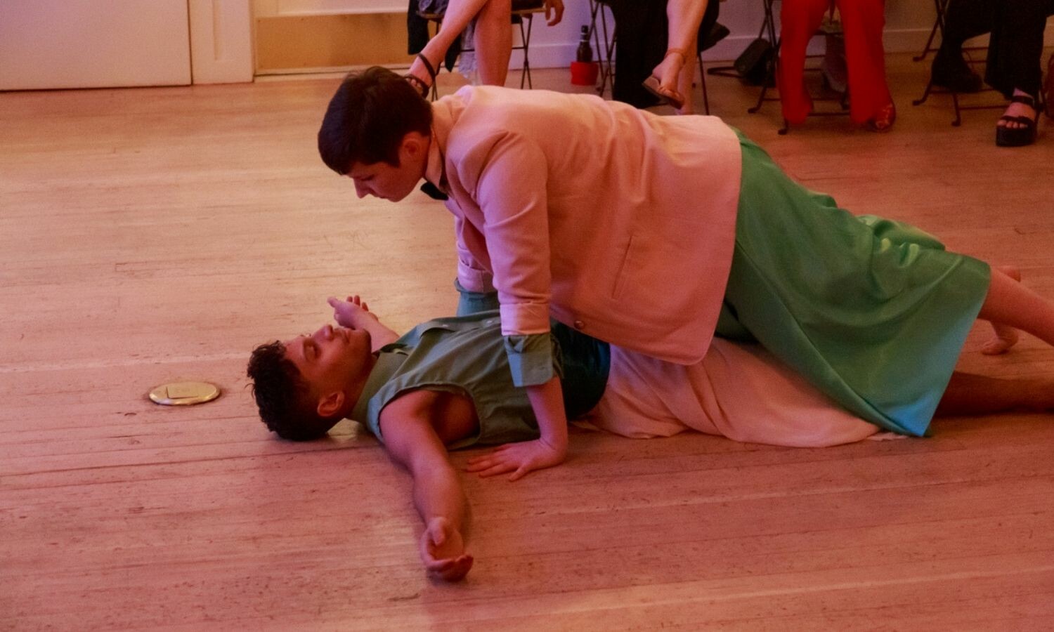 One actor with both arms around the other actor, pinning them to the ground. The actor on the floor with both arms straightened out.