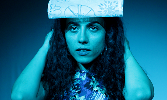 a women holding a folded paper on her head.