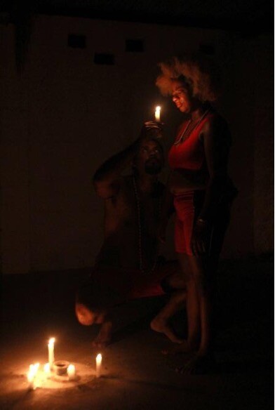 A woman stands over candlelight with a candle in her hands.