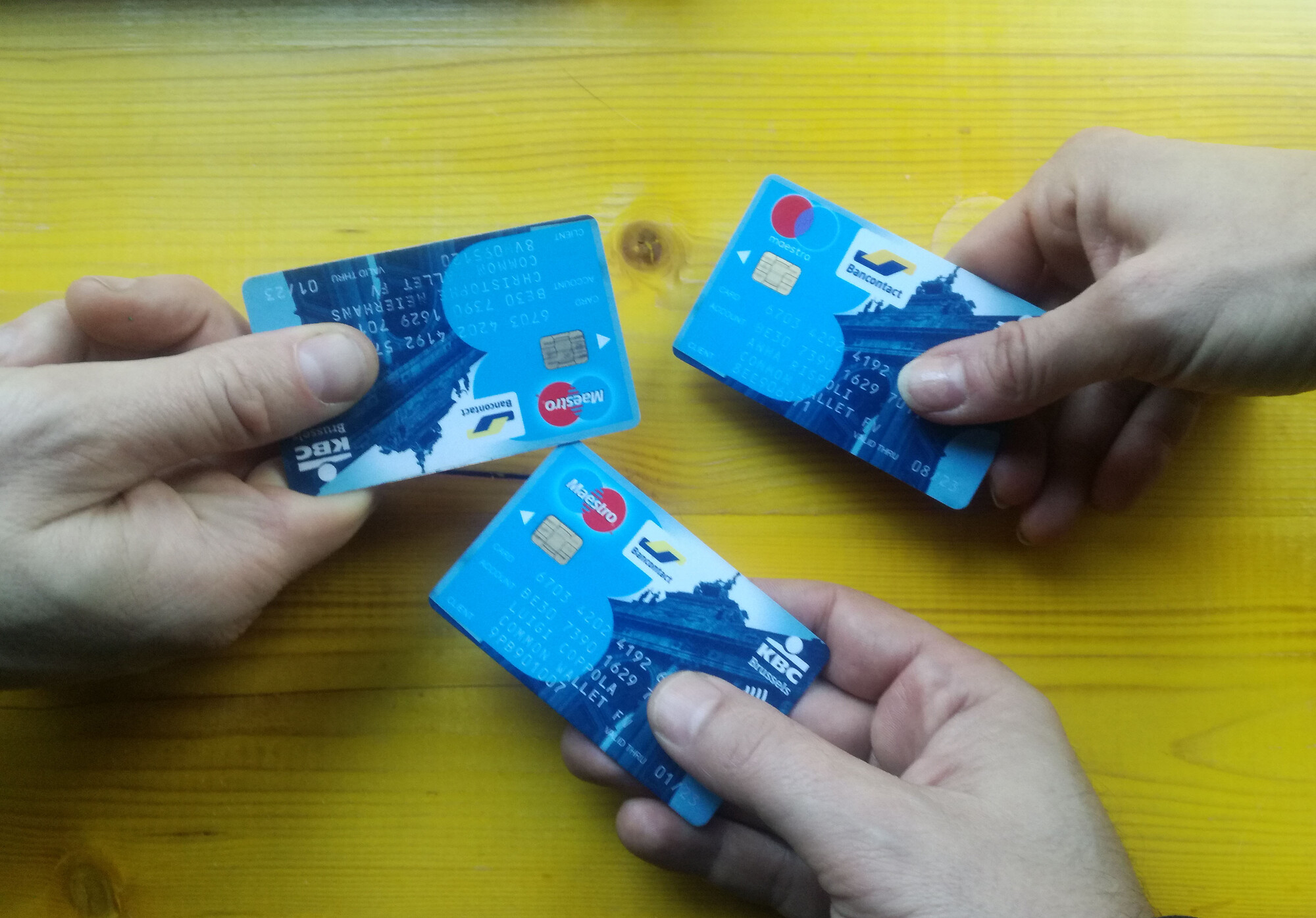 Three people hold their own bank cards that read "Common Wallet" under their names.