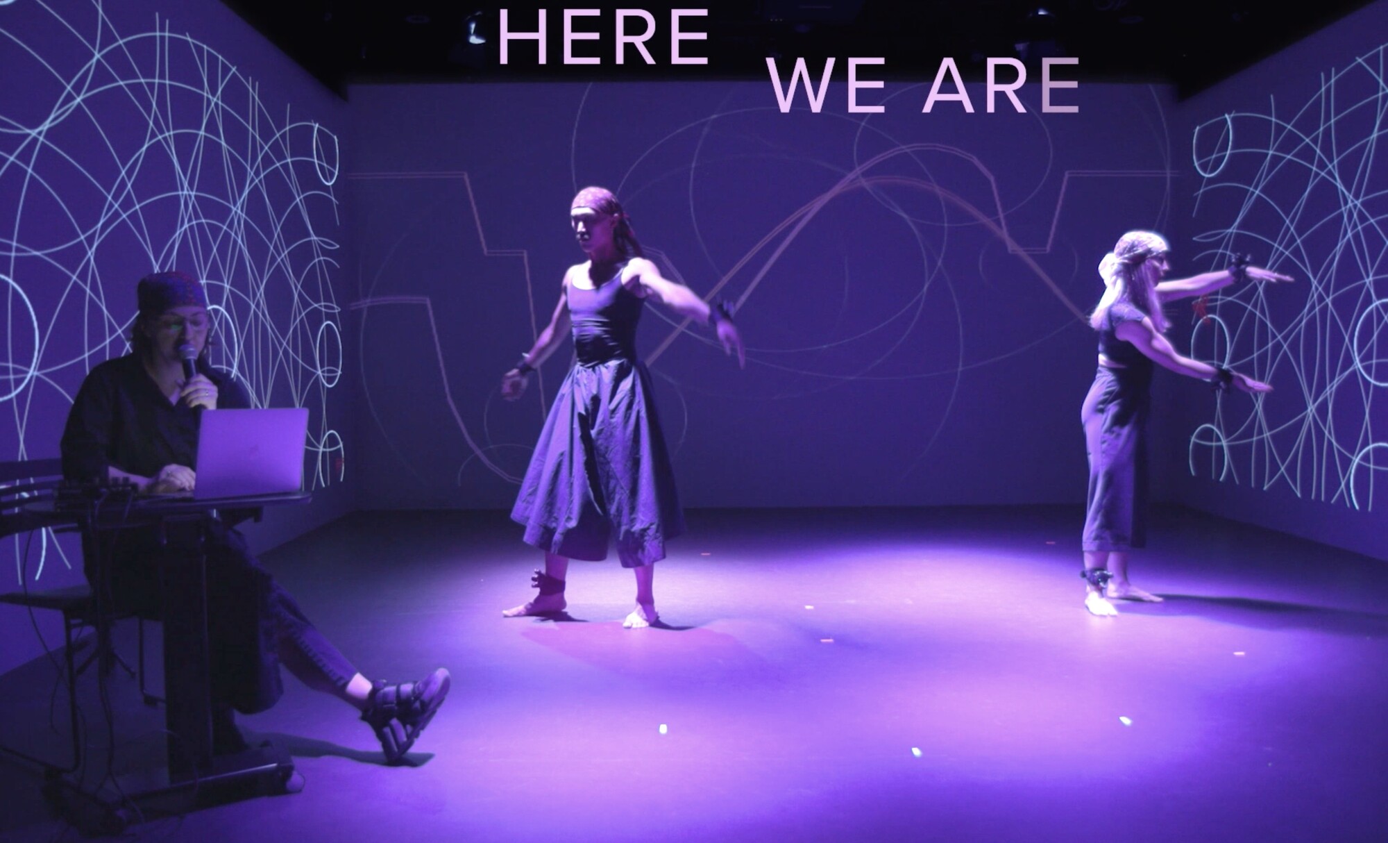 The actors perform in a brightly lit purple space. 