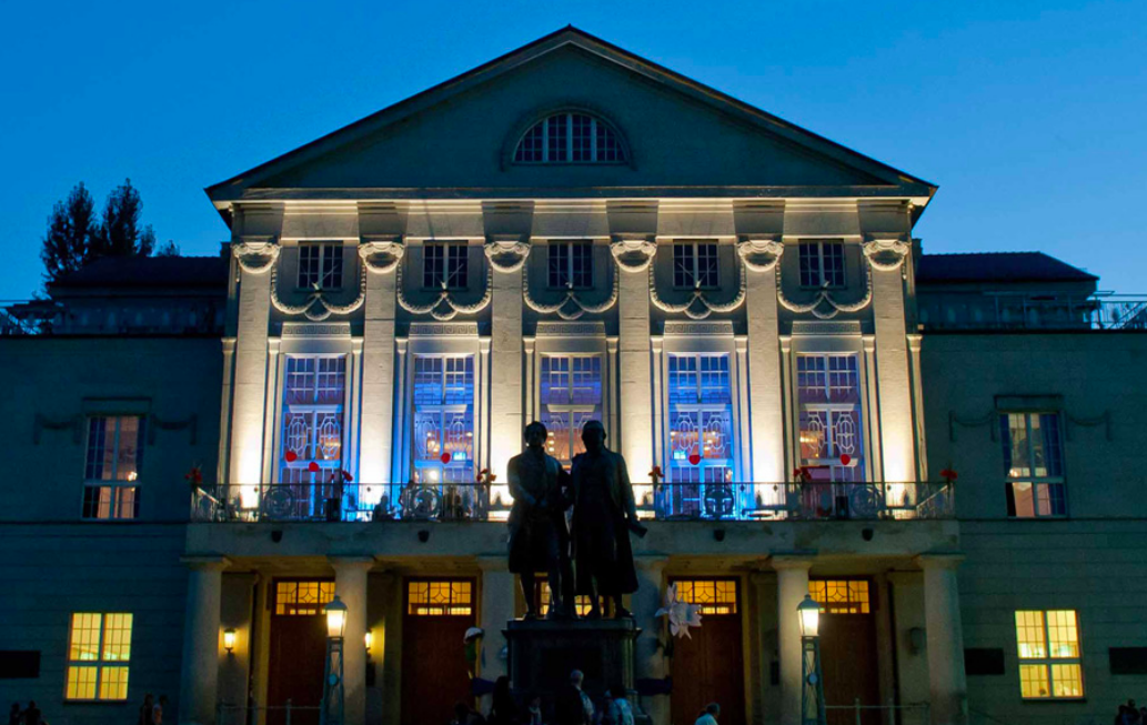 A photo of the outside of a Theatre Building with two statues in front.