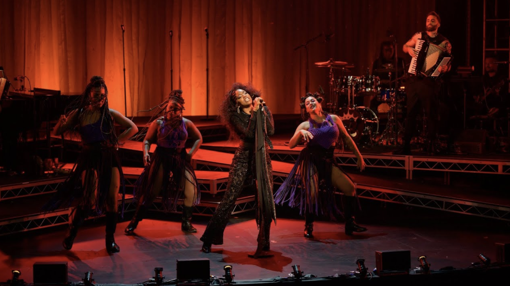 A group sings into microphones onstage.