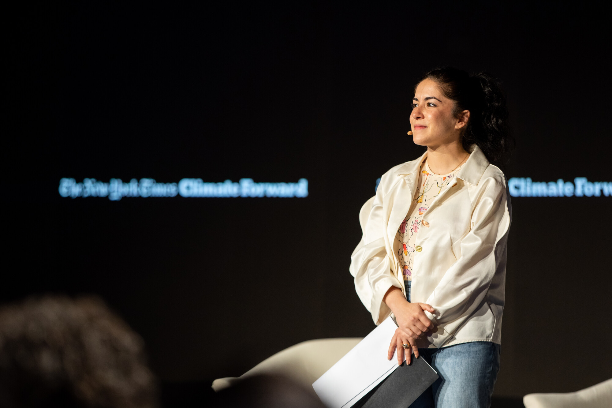 An actor stands with a script in hand in front of a screen.