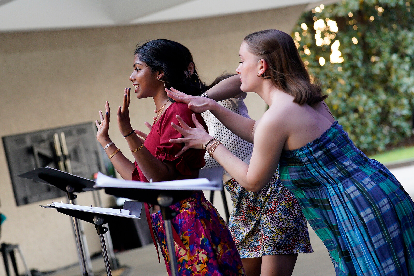 Three performers in brightly colored clothing stand in front of music stands.