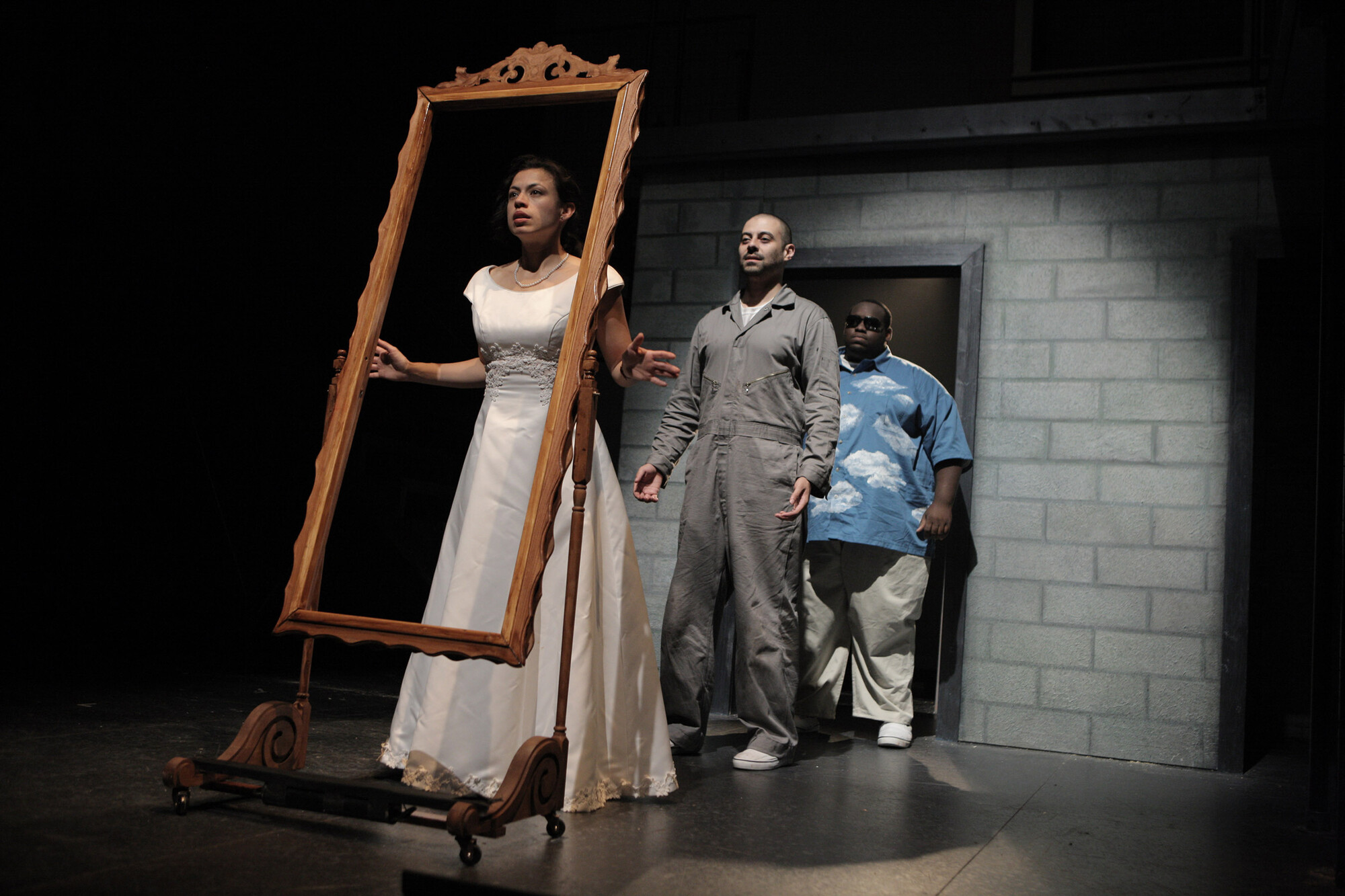 A woman in a white dress holds a picture frame onstage.