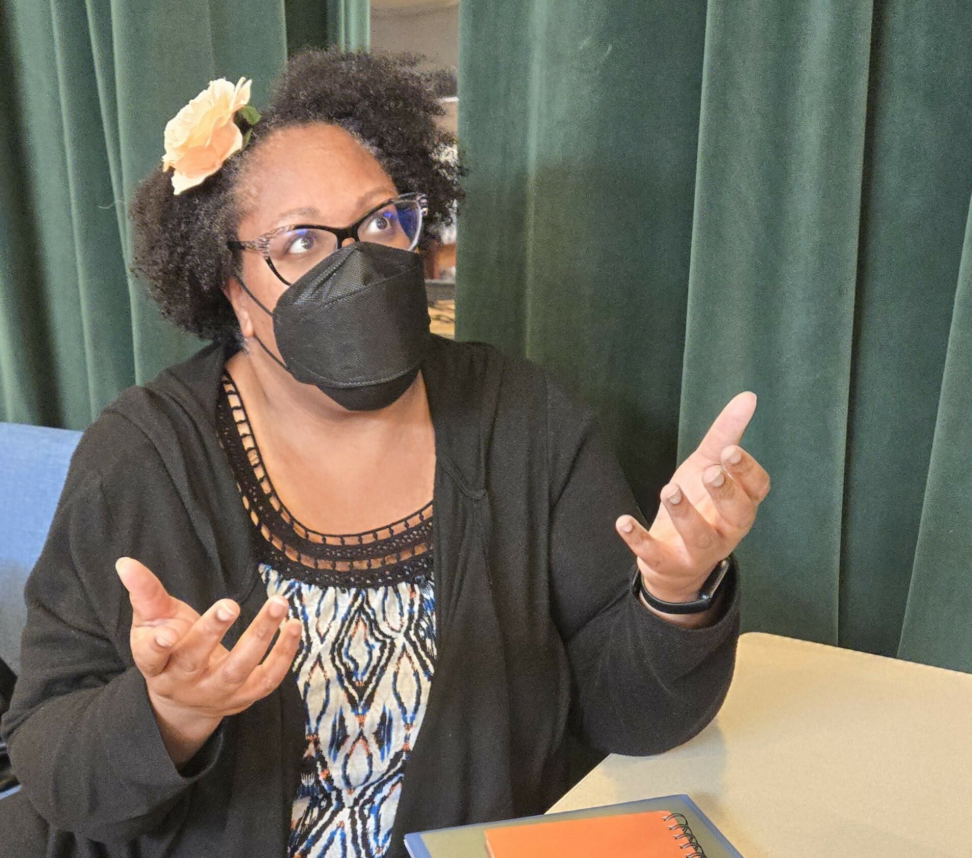 A woman with a flower in her hair speaks during rehearsal.