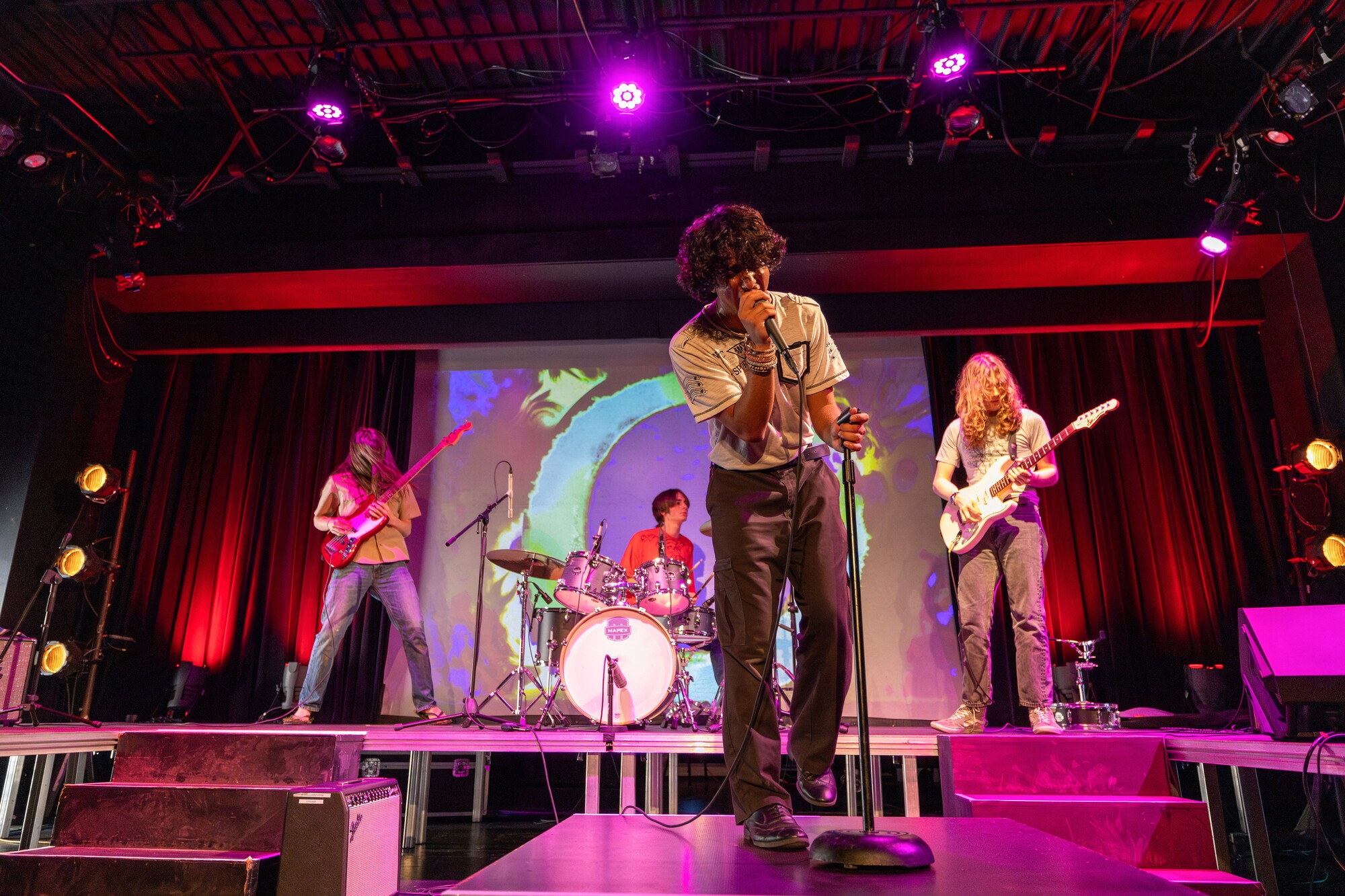 A group of teenagers perform a rock concert onstage.