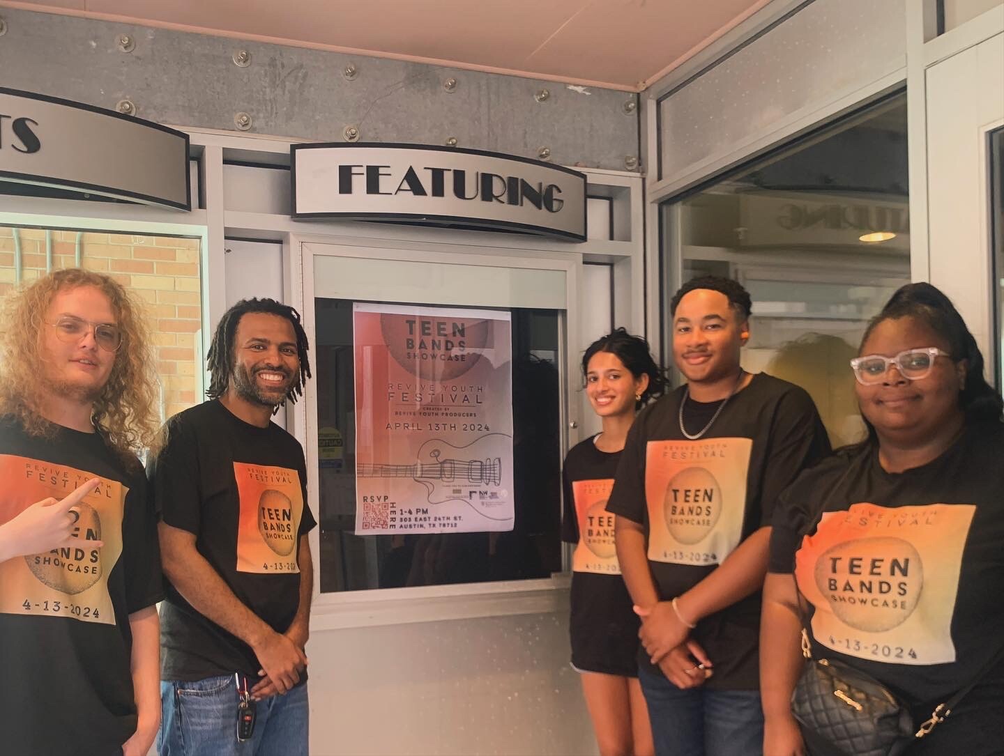 A group of leaders stand in front of a show poster.